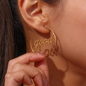 Close-up of a model wearing large 18K gold plated hoop earrings with good script detail