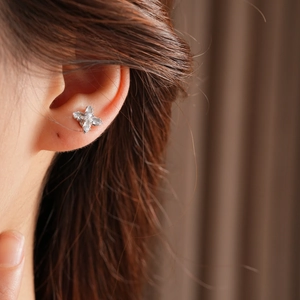 Gros plan de boucles d'oreilles trèfle en argent avec zircons portées sur l'oreille