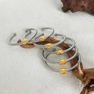 Twisted stainless steel open bracelets with colorful zircon stones on wooden display