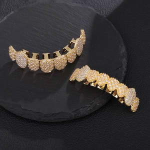 Golden hip hop grillz set with sparkling rhinestones displayed on a black stone surface