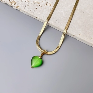 Detailed close-up of 18K gold snake chain necklace with a green heart opal pendant