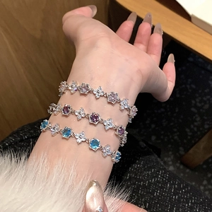 Détail de bracelets fleurs en zircon de luxe en rose, violet et bleu sur le poignet