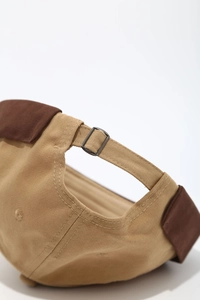 Détail de la boucle métallique et de la sangle réglable sur le bonnet docker en coton