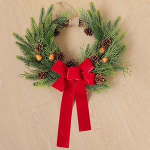 Detail of Christmas wreath with natural pine cones, red velvet bow, and orange berries