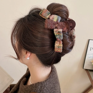 Brown and yellow tweed bow hair claw clip styled on head for an elegant winter look