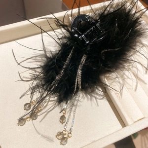 Detail of elegant black feather hair claw with sparkling rhinestone tassel and crystal teardrops