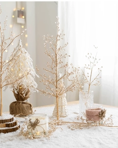 Close-up of golden beaded branches and miniature white LED Christmas tree decoration