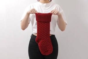 Close-up of red knitted Christmas stocking with textured square pattern and ribbed cuff
