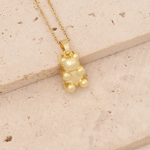 Golden bear pendant necklace with zircon inlay on minimalist beige stone background