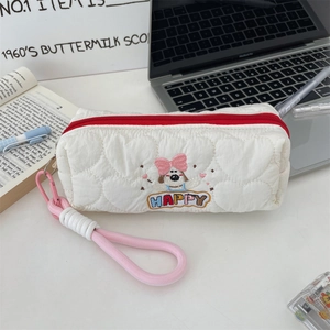 Close-up of quilted pencil case with dog embroidery, red zipper and pink lanyard detail