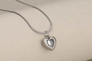 Detail of silver heart pendant with crystal zircon inlay on sleek snake chain necklace