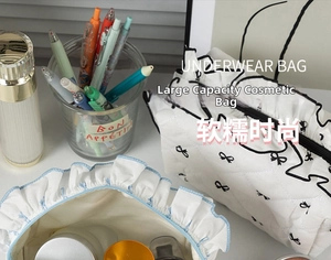 Detail of white quilted cosmetic bags with black bow patterns and ruffle edges