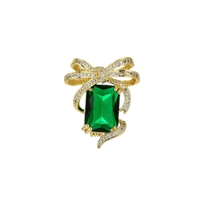 Elegant gold bow brooch with emerald-cut green crystal and micro-pave diamond accents
