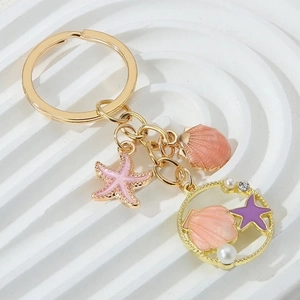Detail of gold starfish and shell keychain with pink enamel and white pearl charms