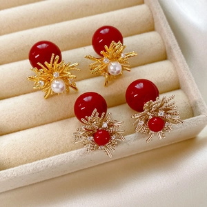 Detail of red resin sphere earrings with golden flower accents and inlaid pearls