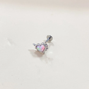 Macro shot of silver heart opal ear stud with iridescent shimmer on a beige background