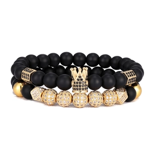 Détails de deux bracelets en pierre noire mate avec couronne dorée et boules en zircon
