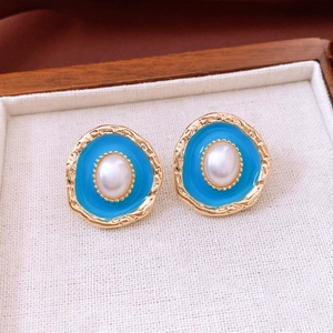 Macro shot of vintage gold stud earrings with sky blue enamel and center oval pearl
