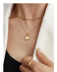 Gros plan sur le collier à pendentif cœur double couche et la bague dorée martelée