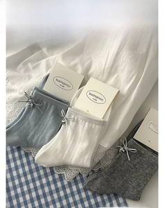 Détail de chaussettes mi-mollet en tricot avec rubans argentés et breloques en forme de cœur