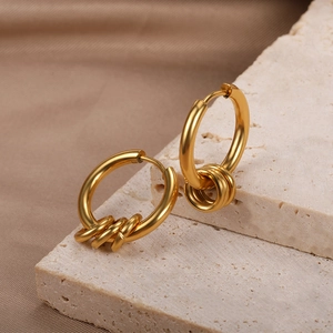 Minimalist gold hoop earrings with three small decorative rings on cream marble base