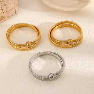 Detail of gold and silver spring magnetic bangles with polished beads on a textured surface