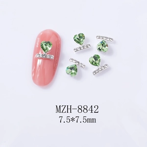 Macro view of green heart rhinestone nail art charms with silver diamond bar, 7.5x7.5mm