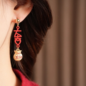 Detail of vintage style enamel lucky bag earrings with red character charms and tassels