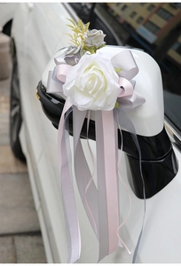 Close-up of a white faux rose and silk ribbons on a car rearview mirror for weddings