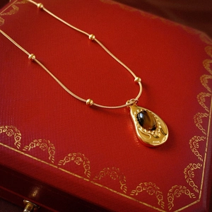Collana dorata in acciaio inox con pietra occhio di tigre a goccia su portagioie retrò