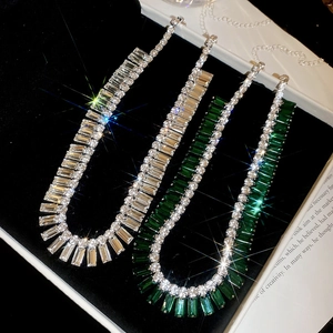 Close-up of luxury rectangular emerald and clear diamond fringe necklaces in a display box