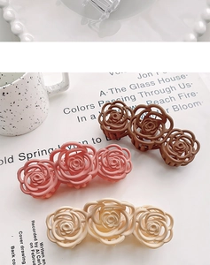 Detailed view of matte camellia flower hair claws in brown, pink and beige tones