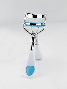 Detail of stainless steel eyelash curler with blue comb teeth and white heart handle