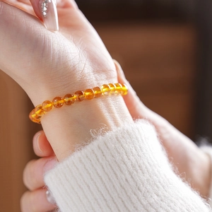 Close-up of amber citrine bead bracelet on a female wrist with warm natural lighting