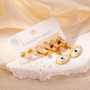 Detail of gold stainless steel evil eye earring set displayed on elegant white stone