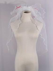 Close-up of white bridal veil featuring small red ribbon bows and delicate wavy edges