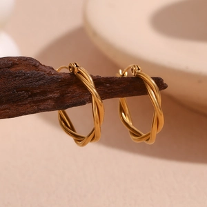 Detail of gold-plated stainless steel twisted hoop earrings on a wooden display stand