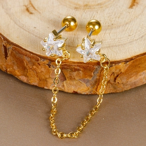 Macro detail of gold star chain earrings with zircon crystals on a natural wood surface