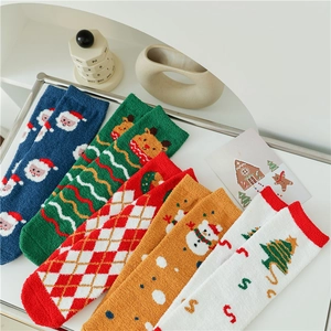 Close-up of thick coral fleece Christmas socks in festive patterns inside a white gift tray