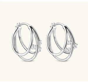 Close-up of silver hoop earrings with sparkling moissanite stones and layered design