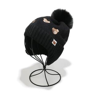 Détail du bonnet en maille côtelée noire avec broderie ours et pompon en fausse fourrure