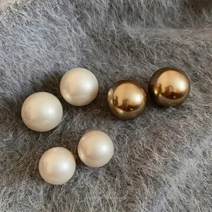 Élégantes boucles d'oreilles perles rondes avec accents dorés sur un support en tissu gris