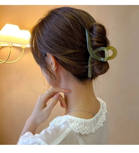 Détail d'une pince à cheveux en résine vert foncé translucide pour un chignon à la française