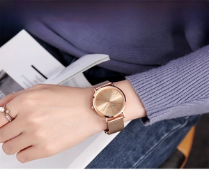 Close-up of a minimalist rose gold mesh watch paired with an elegant pearl ring