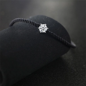 Macro shot of single round diamond in silver six-prong setting on black woven cord