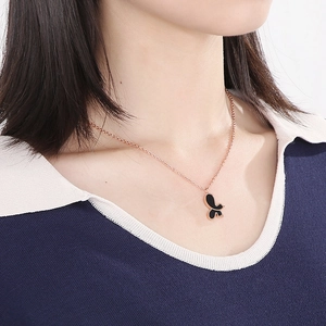 Detail shot of a rose gold butterfly necklace with black shell inlay on a model