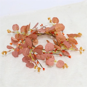 Close-up of harvest candle ring with orange berries and dark eucalyptus leaves