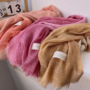 Detailed view of linen scarves in gradient orange, pink and beige with tassel edges