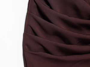 Detailed view of the dark red dress fabric showing elegant draping and pleated texture