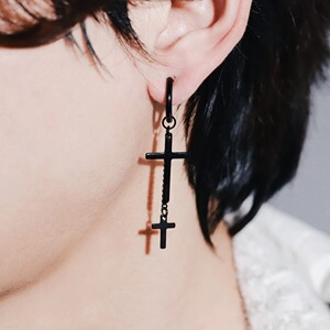 Close-up of black gothic cross pendant earrings worn to show the long chain drop